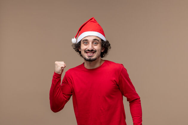 兴奋前视图红色的男性在一个棕色的背景节日情感圣诞节兴奋的表情帽子职业男性