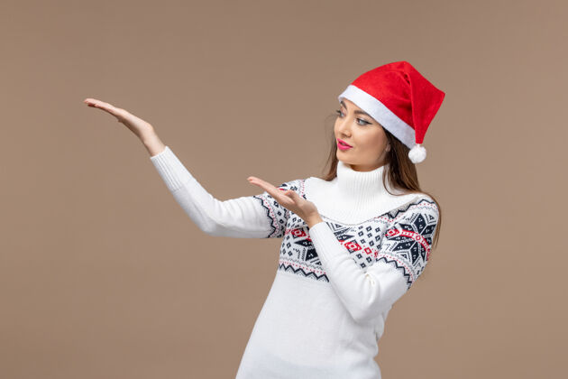 年份正面图棕色背景上戴着红色圣诞帽的年轻女性圣诞感慨新年肖像观点新