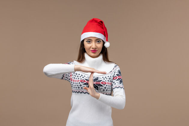 时尚正面图：年轻女性在圣诞假期展示棕色背景上的t字快乐节日浴帽