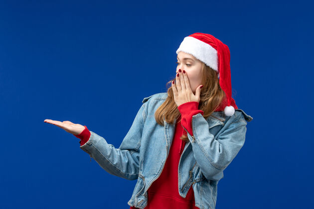 背景正面图：戴着红色圣诞帽的年轻女性 背景是蓝色的圣诞情感色彩表演者情感肖像