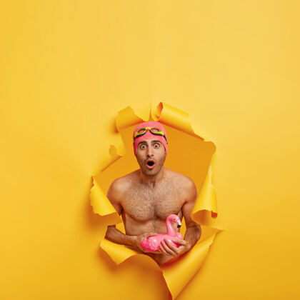 游泳一个赤身裸体的年轻人拿着充气的粉红色火烈鸟的垂直镜头裸体胡茬男