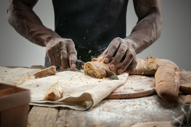 快乐非洲裔美国人用菜刀切新鲜面包的特写镜头幸福男性休闲