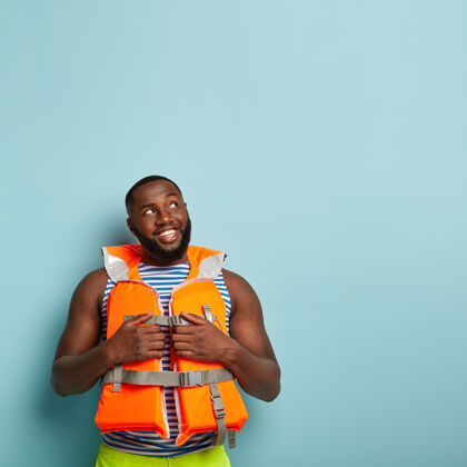 姿势积极的非裔美国人很高兴有一个愉快的游轮 穿着橙色救生衣救生衣高兴安全