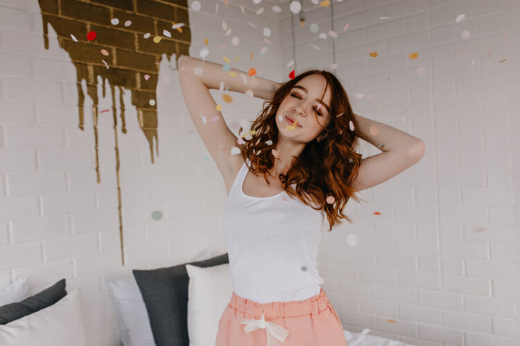 波浪美丽可爱的女孩站在五彩纸屑下美丽的红发女人穿着睡衣在周末微笑开朗漂亮放松