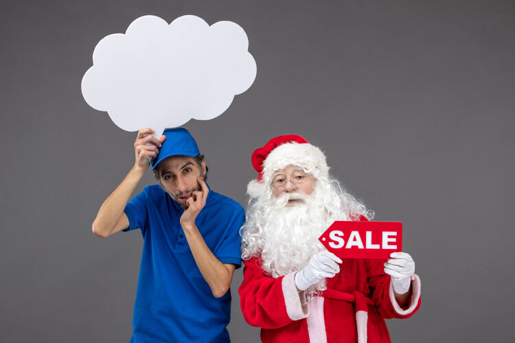 圣诞老人圣诞老人的正面图 男信使手持白云招牌 在灰色墙上出售帽子圣诞老人圣诞老人