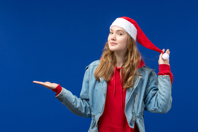 颜色正面图蓝色地板上戴着红色圣诞帽的年轻女性圣诞情感色彩年轻可爱红色