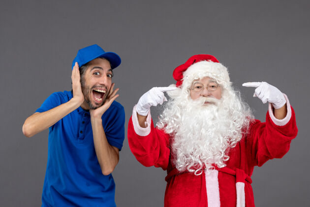 圣诞老人灰色墙上的圣诞老人和男信使的正面图快乐男性圣诞