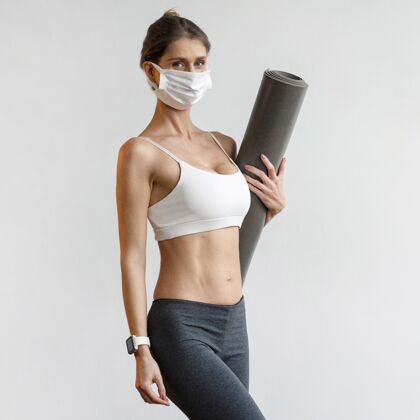 自省戴着医用面罩拿着瑜伽垫的运动女人冥想锻炼冥想