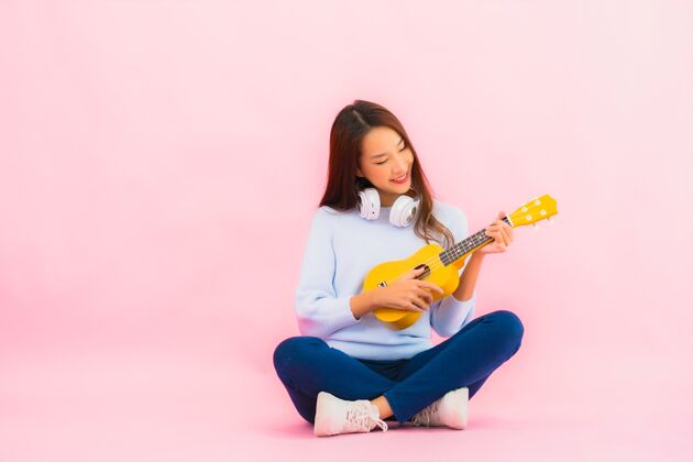 可爱的女孩肖像美丽的亚洲年轻女子在粉红色的隔离墙上演奏四弦琴泰国四弦琴音乐
