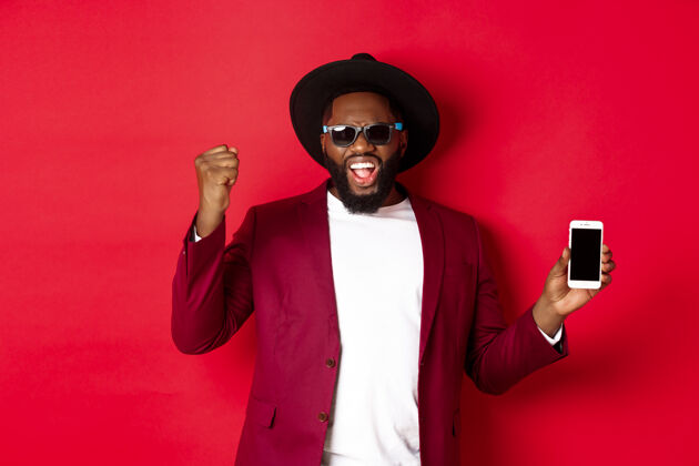 庆祝快乐获胜的黑人展示智能手机屏幕男人手势在线