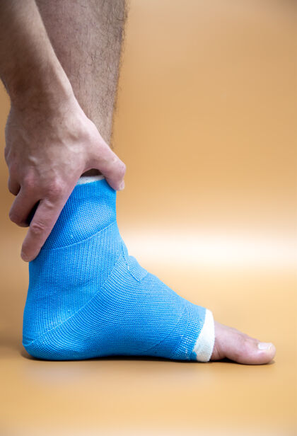 脚踝蓝色夹板脚踝绷带腿上的男性病人彩色模糊的背景运动损伤的概念受伤下绷带