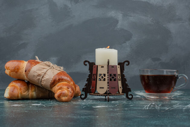 茶大理石桌上放着牛角面包和蜡烛的热茶蜡烛食物香味