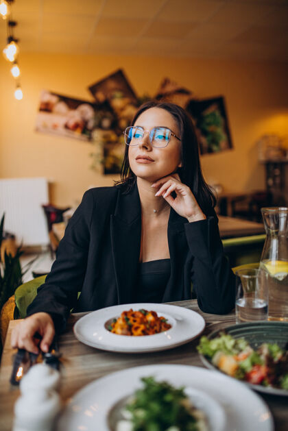 积极在咖啡馆吃意大利面的年轻女人菜西红柿食物