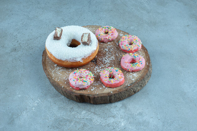 甜食小甜甜圈围绕一个大甜甜圈放在大理石木板上配料糕点糖果