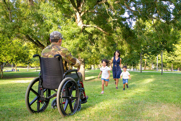 白种人开朗的孩子们和他们的妈妈遇见了军人的父亲 跑向伪装的残疾人退伍军人还是回家的概念跑步返回伪装