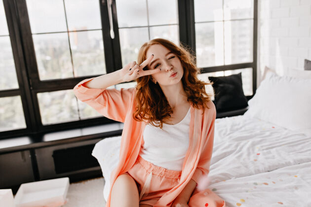和平可爱的红发女士周末早上在自己的公寓里度过穿着睡衣摆出迷人的姿势现代姜成人