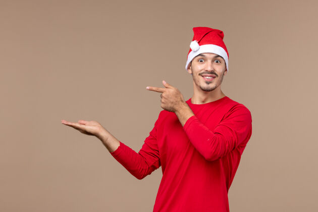 快乐正面图棕色地板上一脸兴奋的年轻男性圣诞节情感假期前面圣诞节人