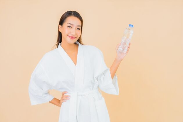 锻炼肖像美丽的亚洲年轻女子与瓶装水喝米色瓶子中国运动