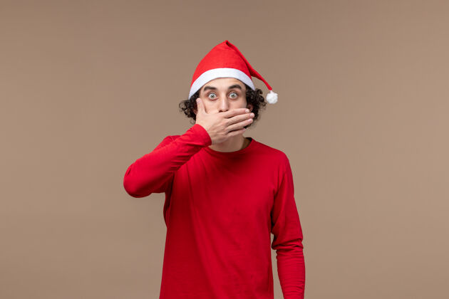 快乐正面图是一个年轻人 在圣诞节的棕色背景下脸上露出惊讶的表情人肖像男性