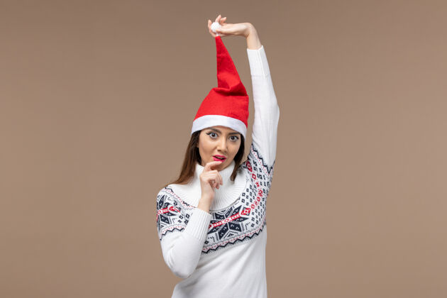 模特正面图：棕色背景上戴着红色圣诞帽的年轻女性圣诞情绪情感成人快乐