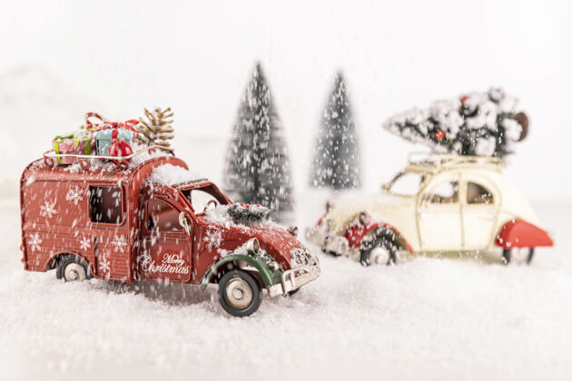 冬天特写的小型汽车玩具人造雪与小圣诞树的背景庆祝人造灯光