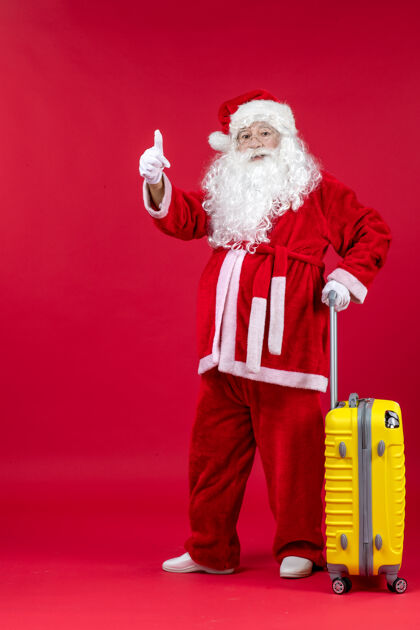 前面红墙上准备旅行的黄包圣诞老人的正视图十二月圣诞快乐男人