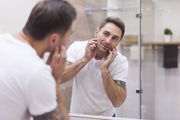 睡衣男人在镜子里检查他的皮肤状况卫生内部检查