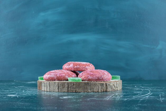 点心在蓝色的木板上涂上粉红色的饼干和marmelades涂层曲奇果酱