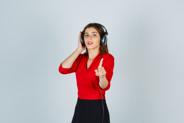 自信戴着耳机的年轻女士 穿着红色上衣 边走边听音乐年轻成功人