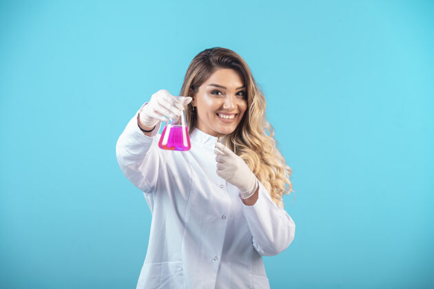 制服穿着白色制服的护士拿着一个装有粉红色液体的化学瓶 感觉很积极医学医院诊所
