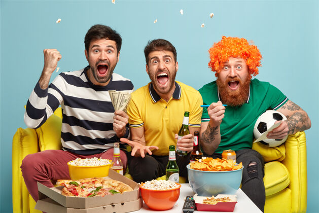 成谊 游戏 赌博 休闲的概念情绪激动的三个男性朋友在家看电视上的足球比赛 握紧拳头 在进球时大喊家电视情绪