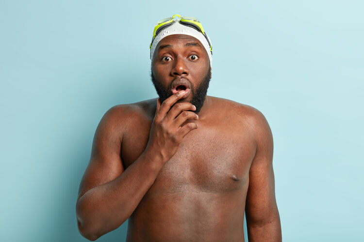 胡须震惊的非洲裔美国游泳教练 留着胡须 屏息呼吸 裸体在室内摆姿势 皮肤黝黑健康 戴泳帽和护目镜 在水中进行爬行训练护目镜健身健美运动员