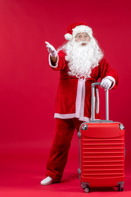 男人圣诞老人的正面图 红色的墙上挂着他的红色袋子时尚人们服装