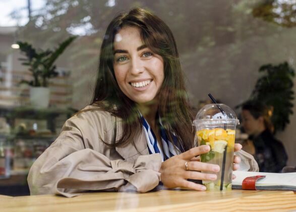 提神咖啡馆里快乐女人的肖像 带着新鲜柠檬水和耳机热带水果异国情调异国情调水果