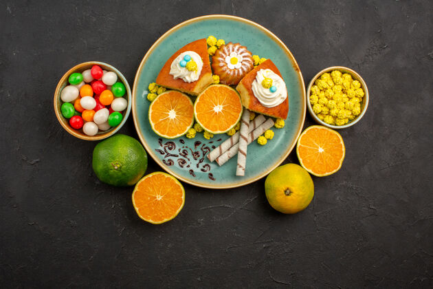 柑橘顶视图美味蛋糕片与新鲜切片橘子和糖果在黑暗中茶新鲜甜食