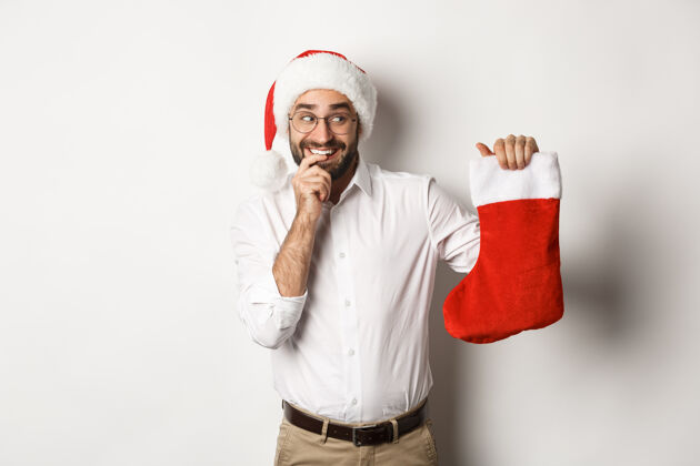 微笑圣诞快乐 节日概念看起来快乐和好奇的成年男子在圣诞节袜子 收到礼物 戴圣诞帽商人西装圣诞老人