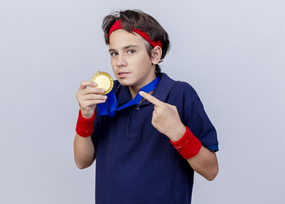 冠军年轻帅气的运动男孩脖子上挂着奖牌 拿着奖牌指着奖牌腕带看着指着