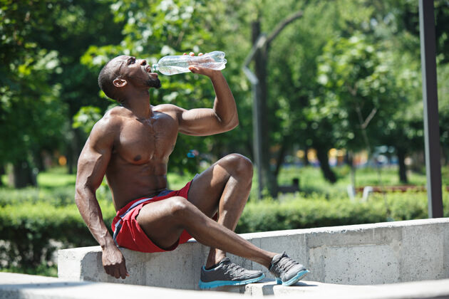 强壮健身运动员在体育场休息和运动后喝水非裔或非裔美国男子在城市户外健身 健康 生活方式的概念成就非洲运动