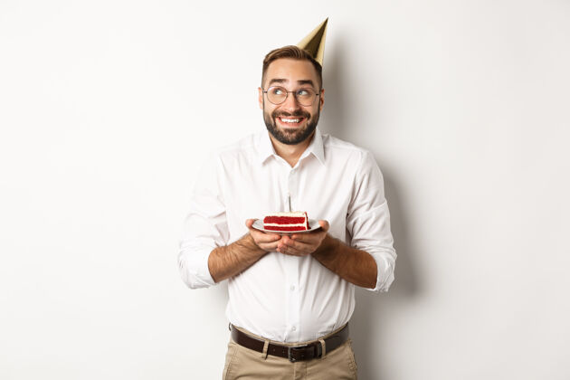 兴奋节日和庆祝快乐的男人有生日聚会 在生日蛋糕上许愿 微笑着 站着庆祝帽子休闲