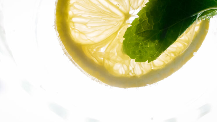 刷新柠檬片和薄荷叶漂浮在冷柠檬水里的微距照片自制热带味道