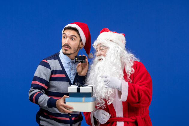 举行正面图：圣诞老人和手持礼物的年轻男性人情感男人