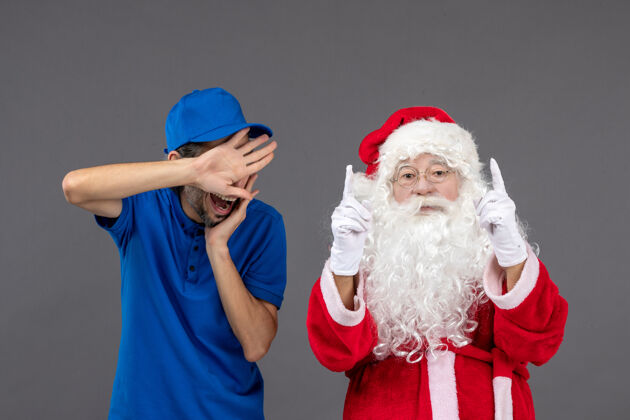 圣诞老人灰色墙上的圣诞老人和男信使的正面图快乐服装圣诞老人