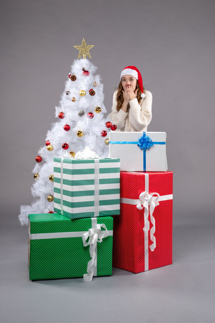 圣诞树年轻的女性在灰色的圣诞礼物周围年轻购物圣诞