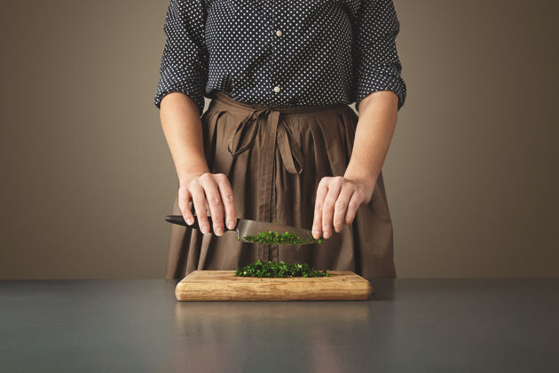 美食老蓝桌上木板上切碎的绿欧芹上面 女人拿着刀不可辨认的主妇膳食自然配料