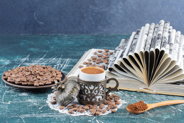 咖啡豆一杯泡沫咖啡 一盘咖啡豆和一本大理石桌上的书饮料咖啡豆咖啡