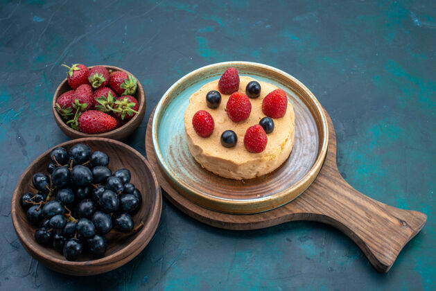 面团前视小蛋糕与新鲜草莓放在深蓝色桌上水果浆果蛋糕烤甜糖面团馅饼小的可食用的水果烘焙