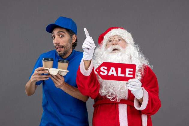 圣诞老人圣诞老人的正面图 男信使拿着售货笔 灰色墙上挂着咖啡男人快递前面