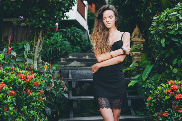 晒黑热带花园里年轻漂亮性感的女人 在泰国度暑假 苗条瘦削的棕褐色身材 带蕾丝的小黑裙 自然的造型 感性的 放松的 优雅夏天服装