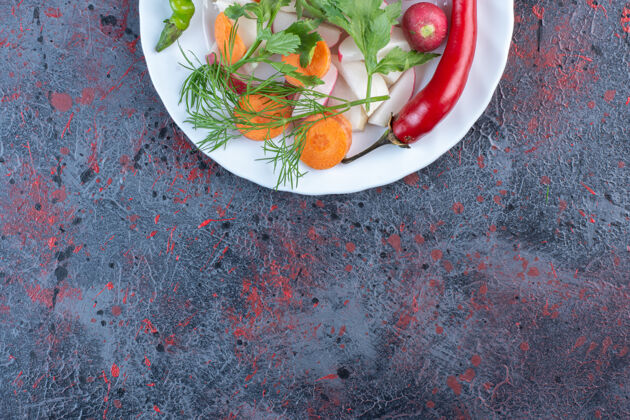 膳食把美味的蔬菜放在黑桌子上的白盘子里顶部青椒绿色