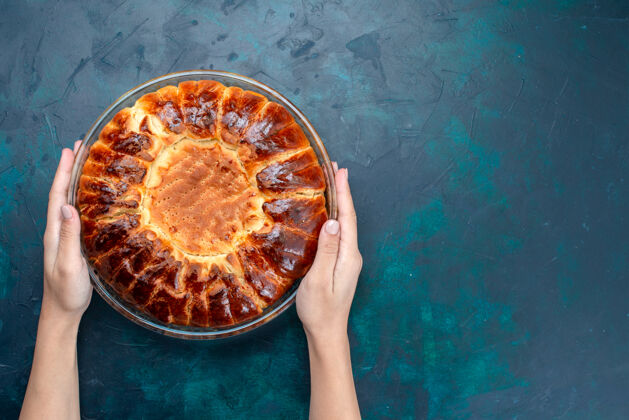 烘焙顶视图美味的烤蛋糕圆形形成甜内浅蓝色背景上的玻璃锅玻璃顶部蛋糕